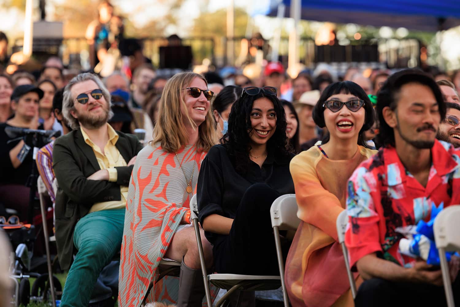 Students seated in rows of lawn chairs.