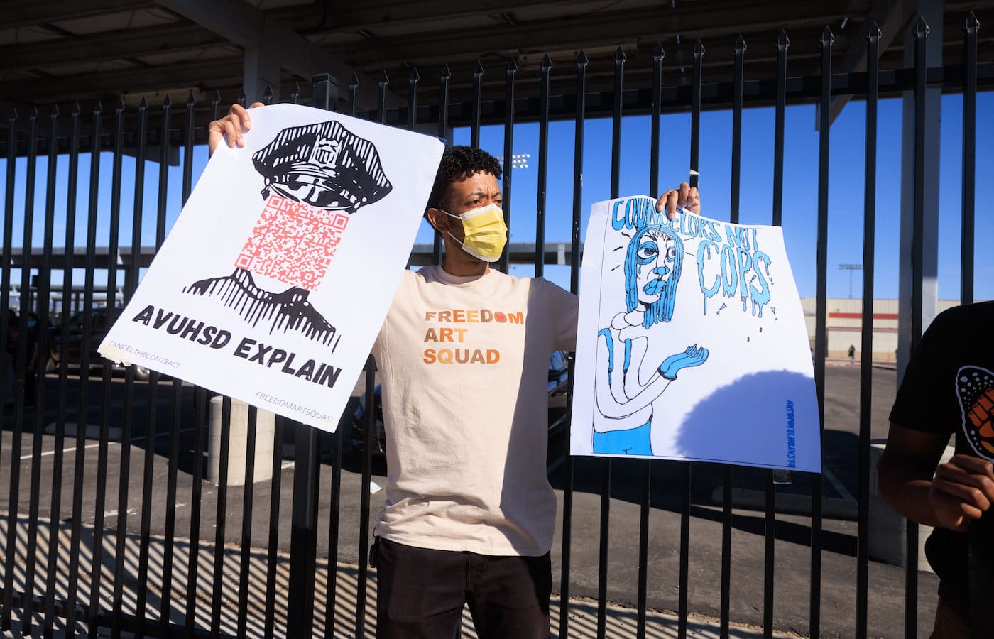 a man in mask carries two protest signs