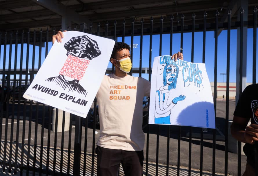 a man in mask carries two protest signs