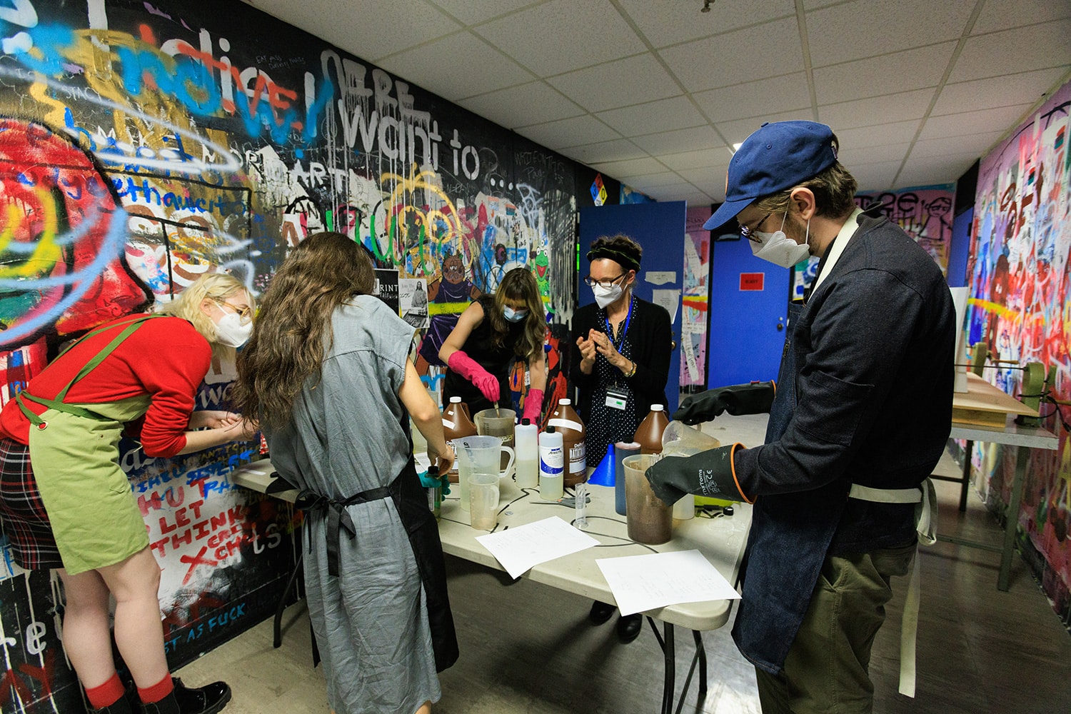 Group of people wearing masks work around a table.