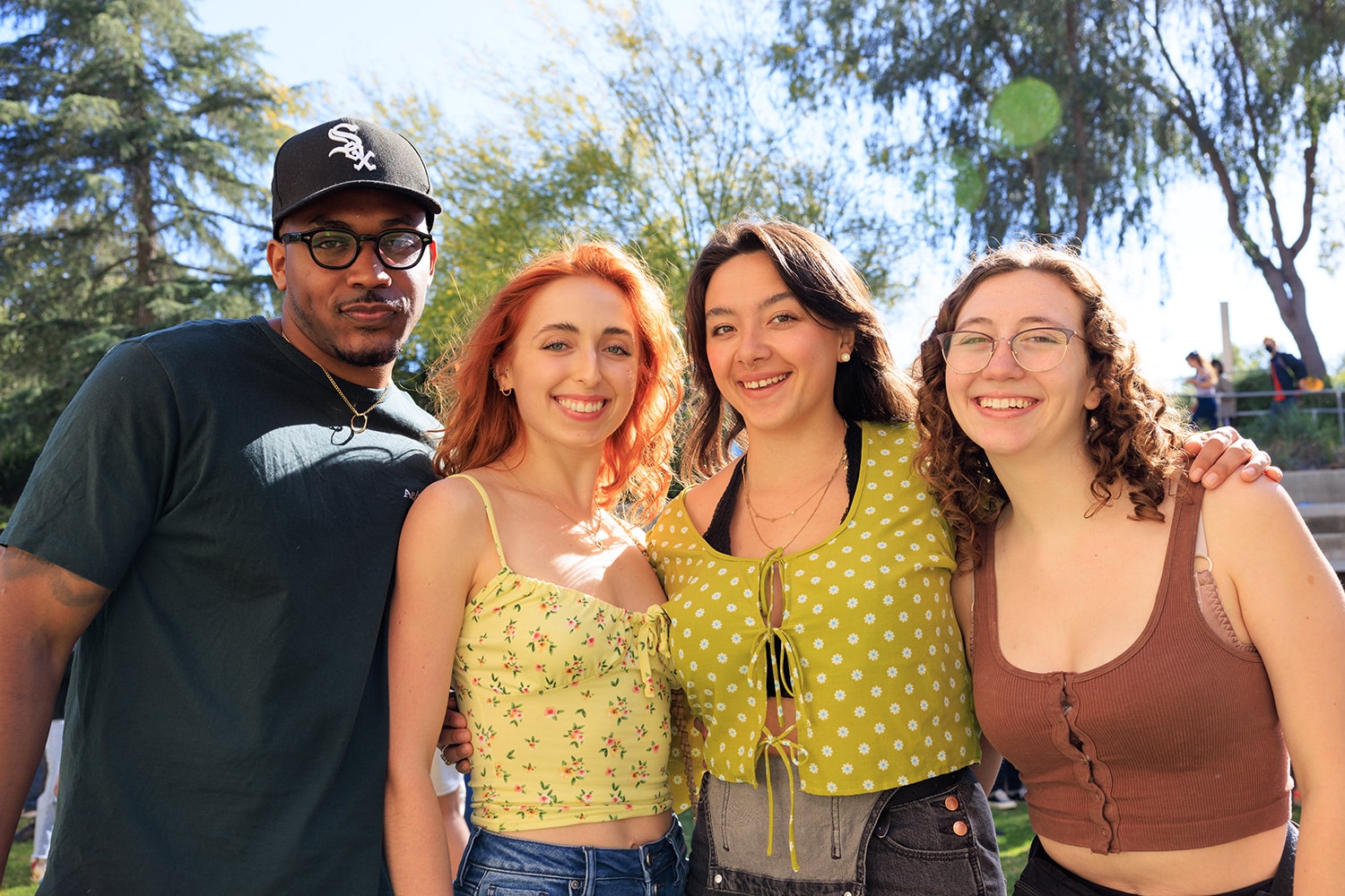 Four students standing outdoors smile for the camera.