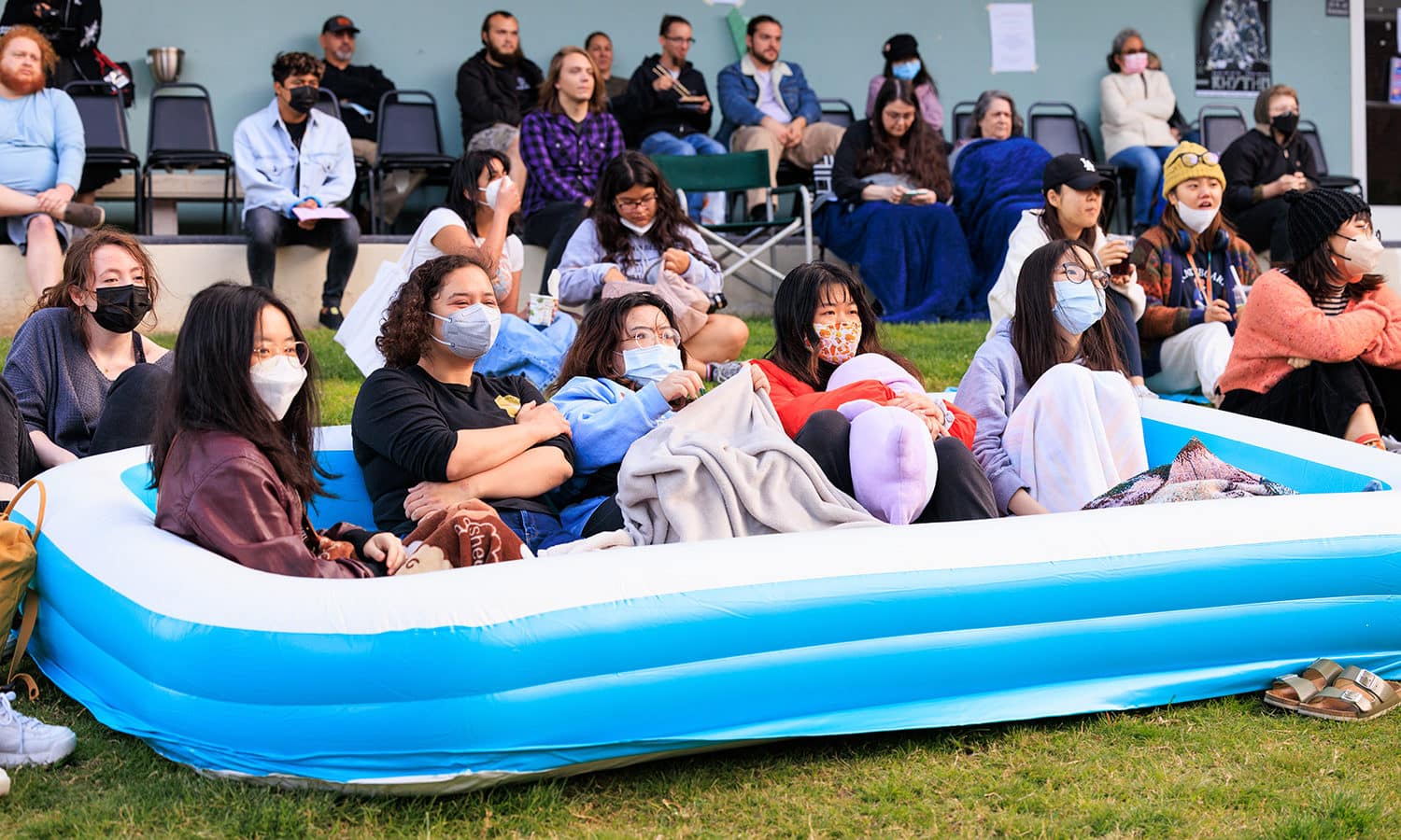 Group of students sitting in an inflatable pool on the lawn.