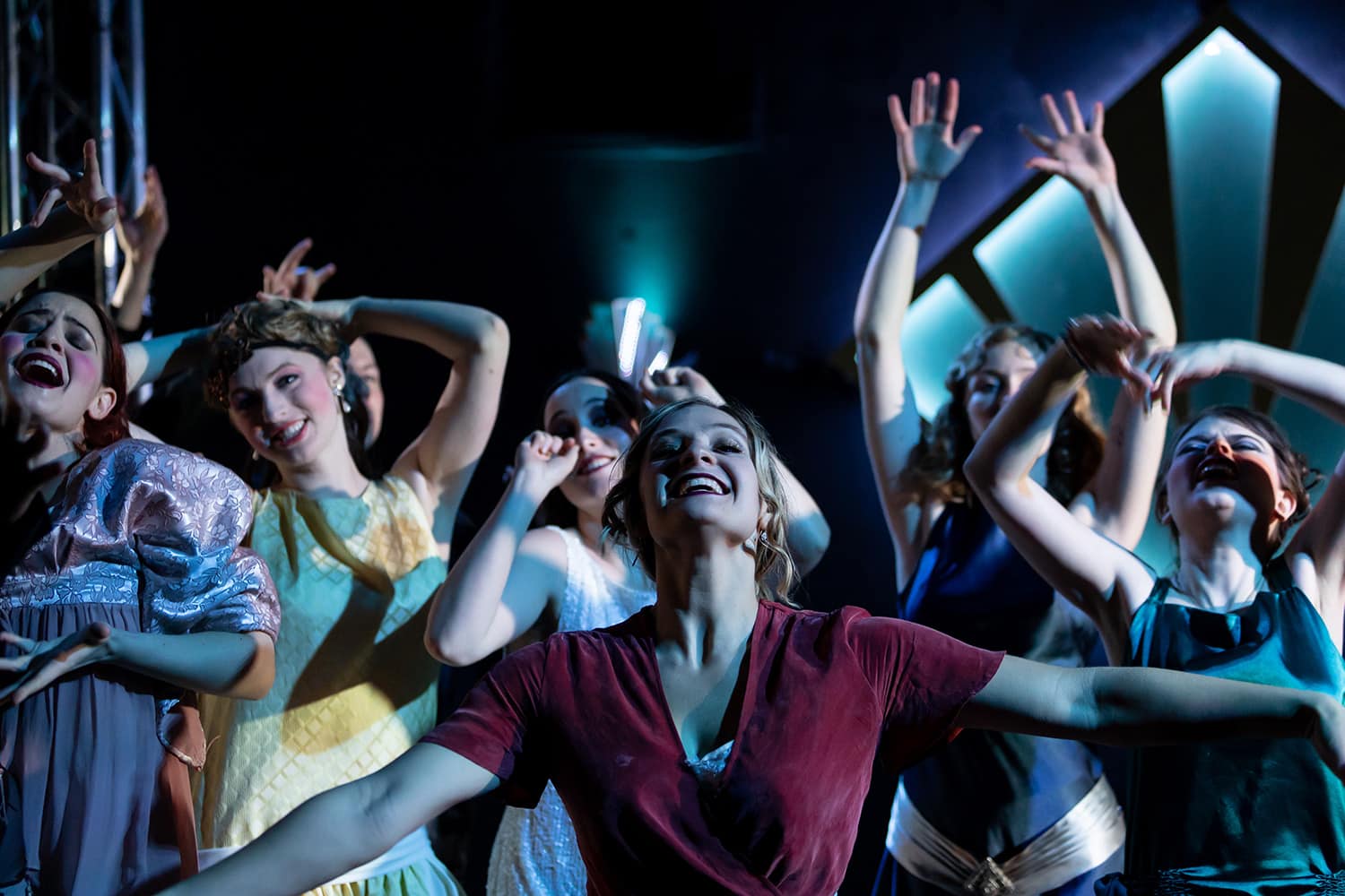 A group of women on stage posing with arms up