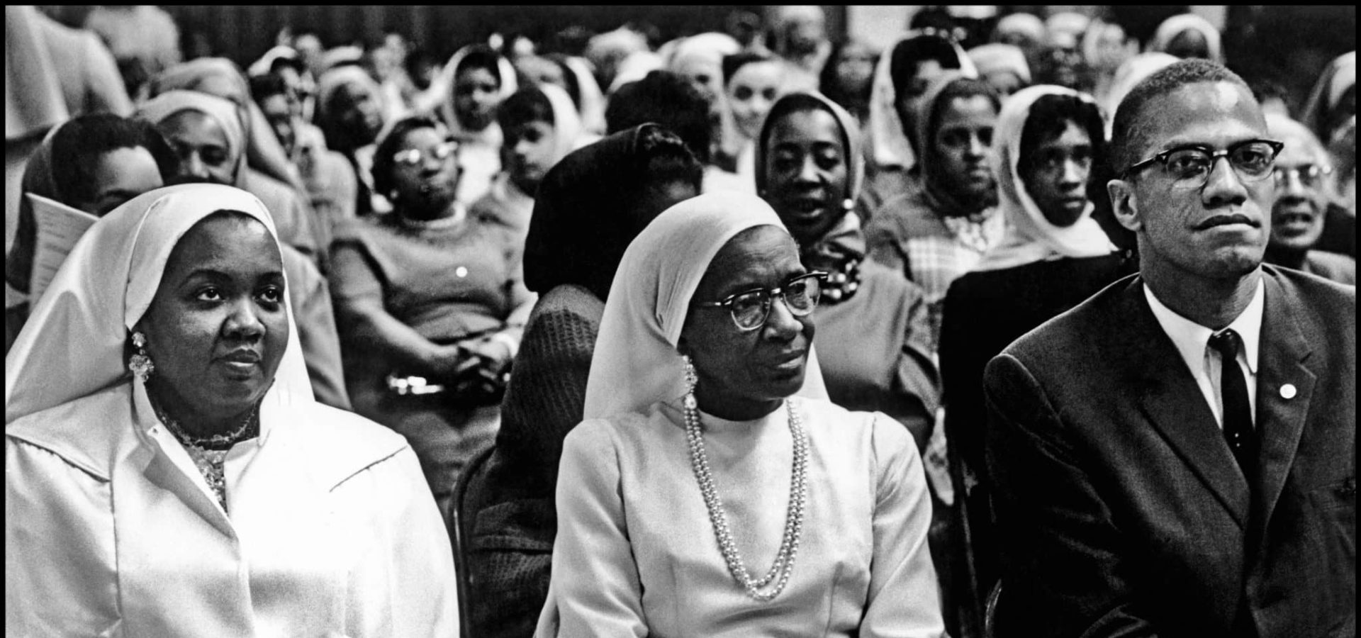 Black Muslims Meeting. USA. Chicago, Illinois. 1962. Daughter and wife of Elijah Mohammed with Malcolm X. | Photo: Eve Arnold/Magnum Photos.