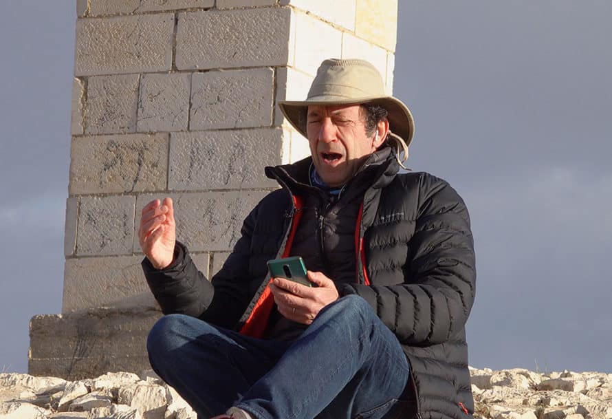 man in hat and coat sitting and talking