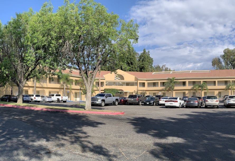 A tan building in the middle of a parking lot