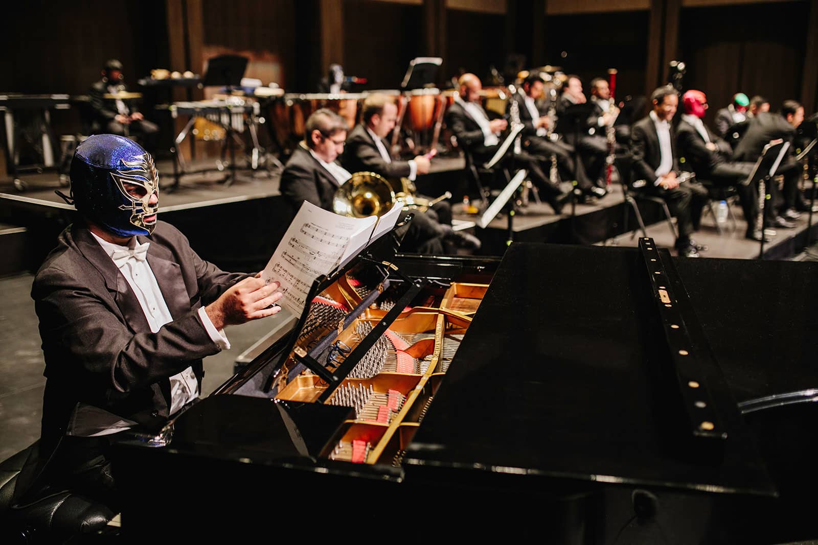 Pianist with blue and black luchador mask turns sheet music