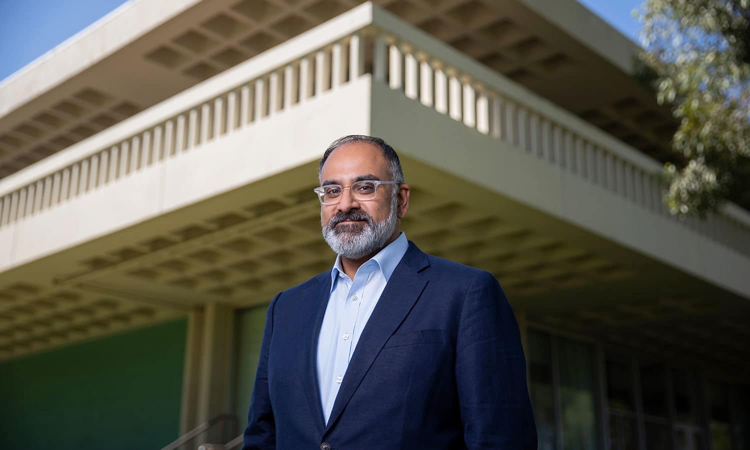 President Rajan in navy tuxedo standing outside Main Building