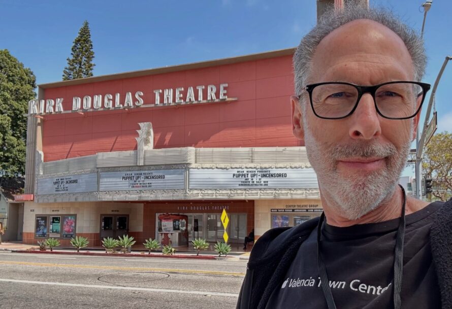 A man with glasses, Allan Trautman, stands in front of a theater.