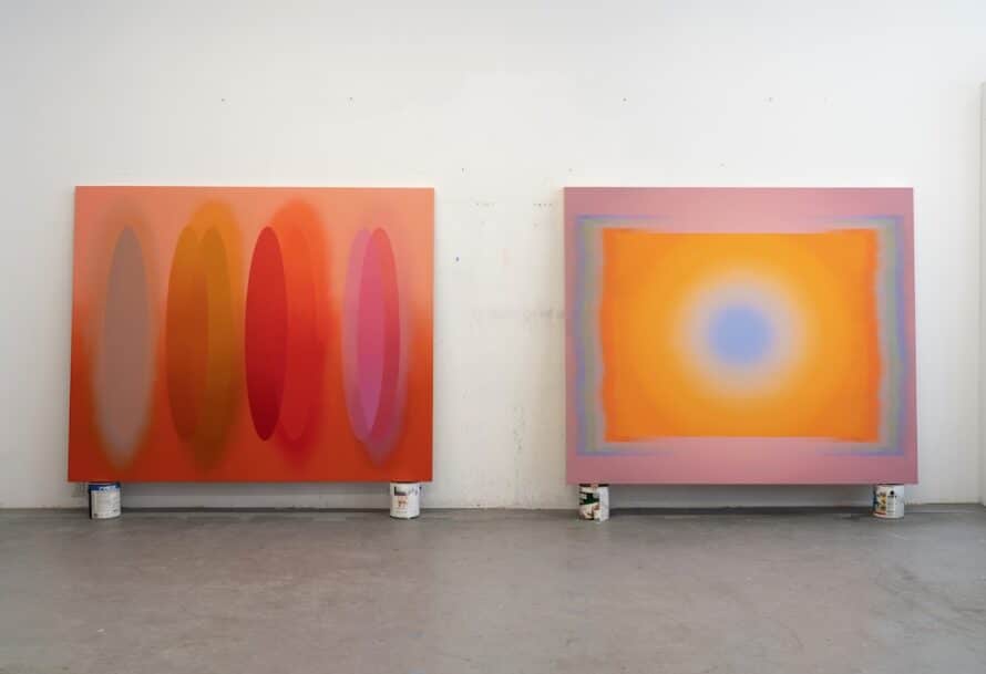 Two paintings with vibrant colors against a white wall.